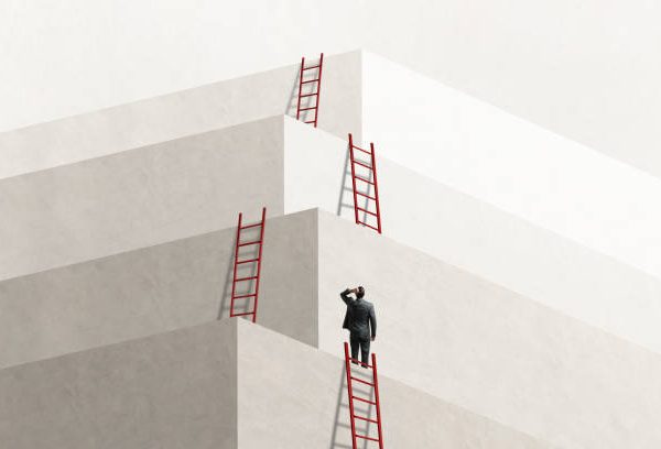 A man looks up at a series of ladders that lead him to the next level, eventually reaching the top.